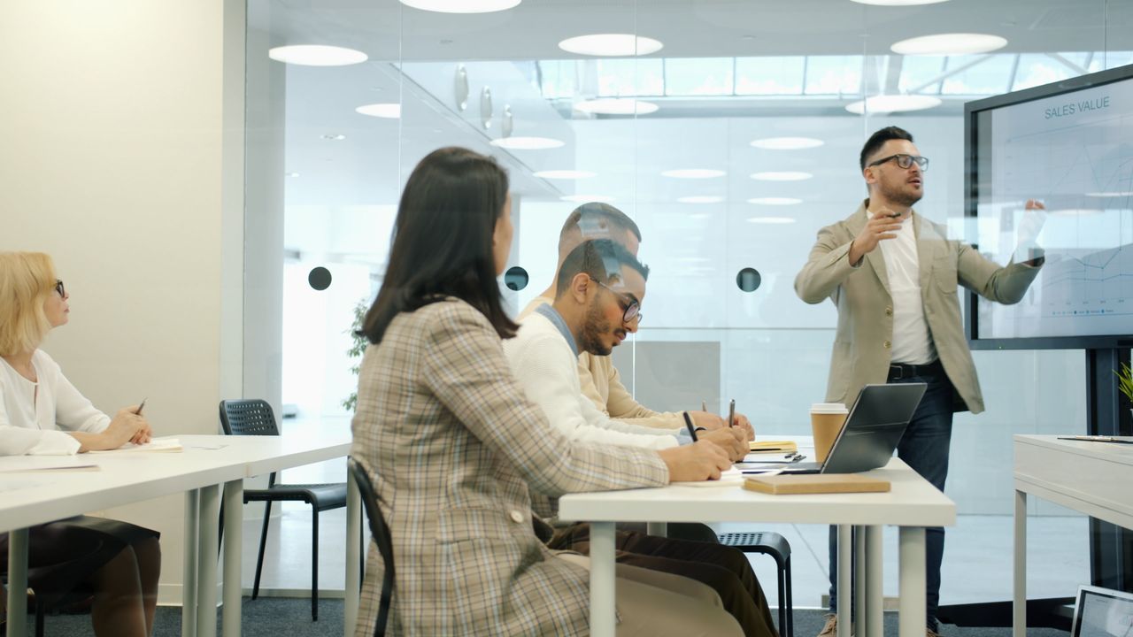 Professionals engage in a business presentation within a modern, light-filled office space.